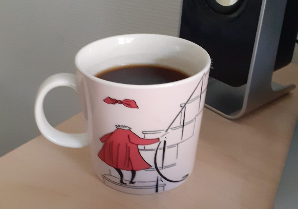 Ninni näkymätön tyttö -muumimuki pöydällä kaiuttimen edessä