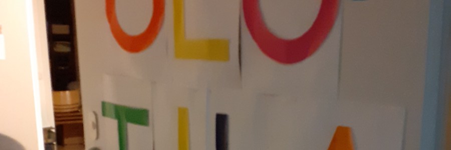 Valkoinen ovi, johon on kiinnitetty värikkäin kirjaimin kirjoitettue teksti: olotila