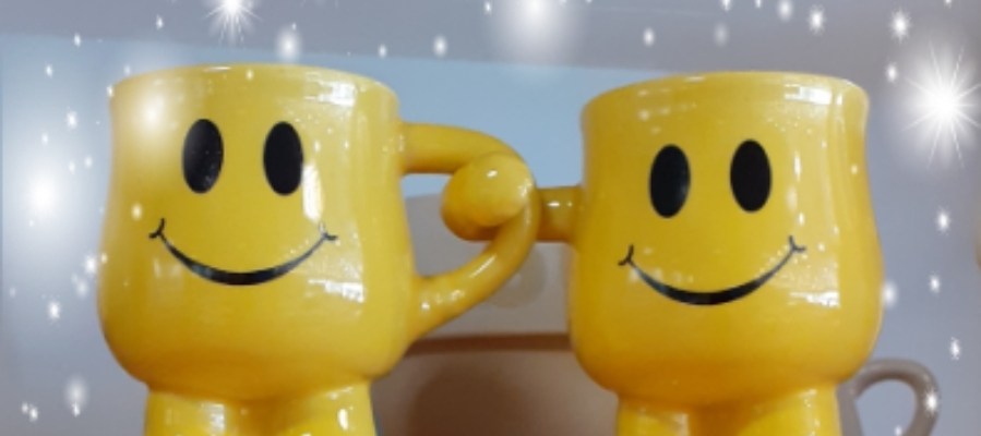 Jalalliset hymiökahvikupit, joista toinen pitää kahvallaan kiinni toisen kupin korvasta.