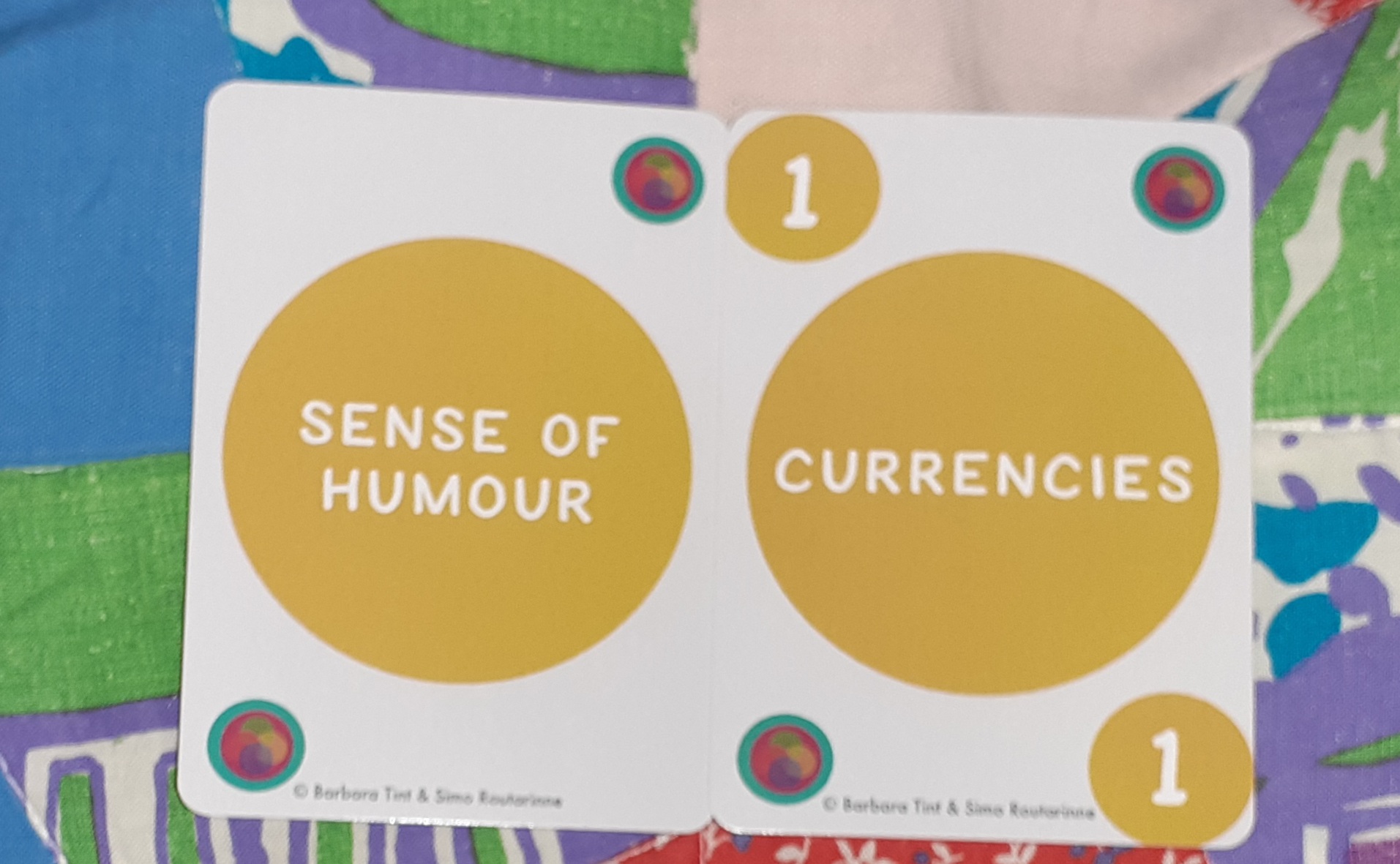 Kaksi statuskorttipakan korttia. Keltainen vahvuuskortti Sense of humour. Vahvuuskortin määrän ilmaisema Currencies-kortti, jossa on arvo 1.