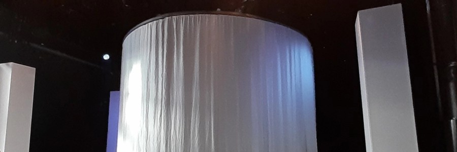 Sultanaatti näytelmän lavastus: kaksi valkoista kangastornia laidoilla ja keskellä pyöreä valkealla kankaalla verhottu tila.