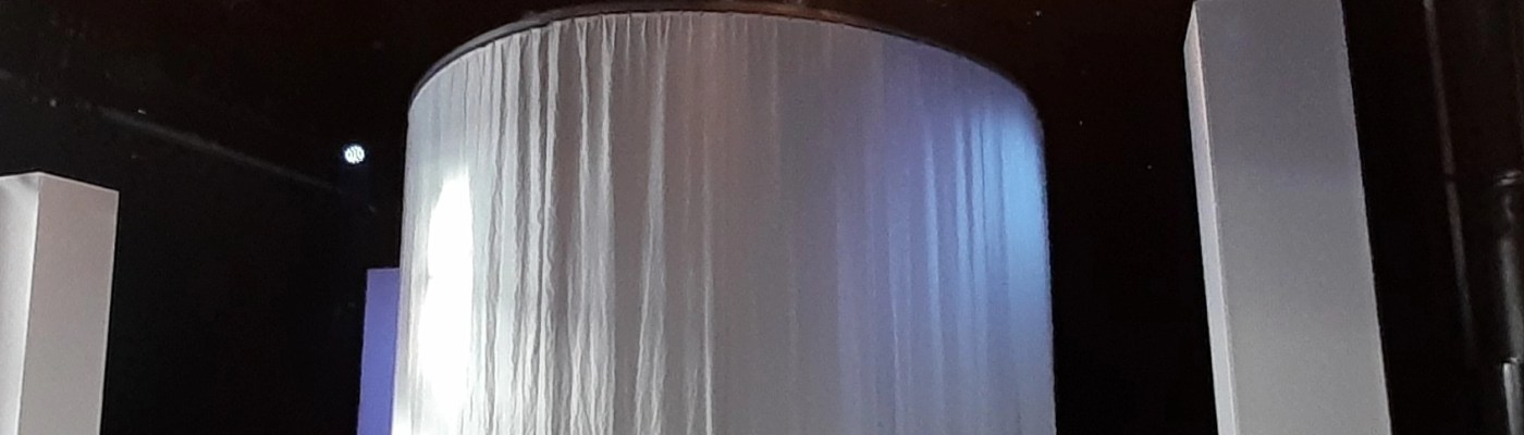 Sultanaatti näytelmän lavastus: kaksi valkoista kangastornia laidoilla ja keskellä pyöreä valkealla kankaalla verhottu tila.